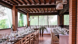 A long dining table set with chairs, a brick wall, and a wooden ceiling. - Girasole in San Gimignano (San Gimignano)