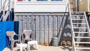 Un edificio frente a la playa con una terraza de madera, una escalera y un letrero.