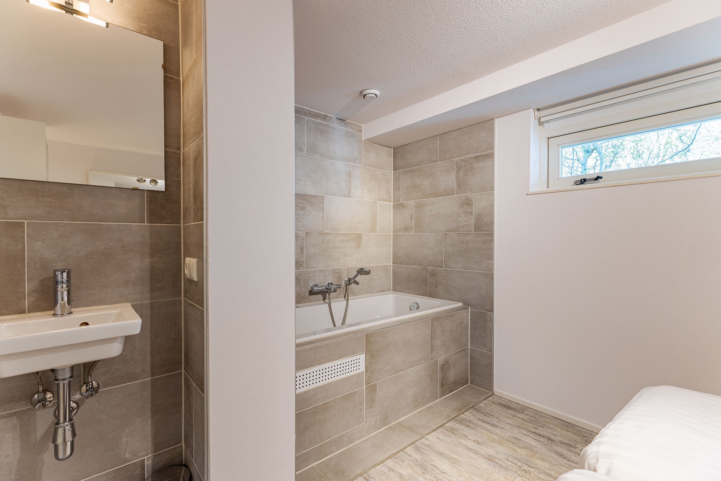 Une salle de bain avec un lavabo, une baignoire et une fenêtre.