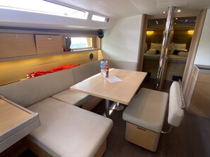 A compact, well-lit interior with a seating area, a small table, and a kitchenette. - Caribbean Dream: Sun-soaked Sailing Adventure from Tortola, Islas Vírgenes Británicas (Road Town)