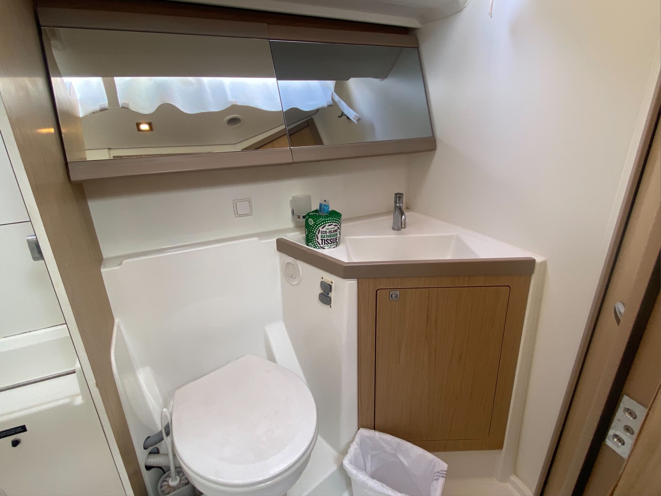 Een kleine badkamer met toilet, wastafel en spiegel.