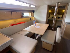 A compact, well-lit interior with a dining area, a bench, and a small kitchenette. - Caribbean Dream: Sun-soaked Sailing Adventure from Tortola, Islas Vírgenes Británicas (Road Town)