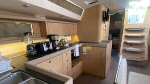 Una cocina compacta equipada con tostadora, hervidor y licuadora, un lavamanos pequeño y armarios de madera.