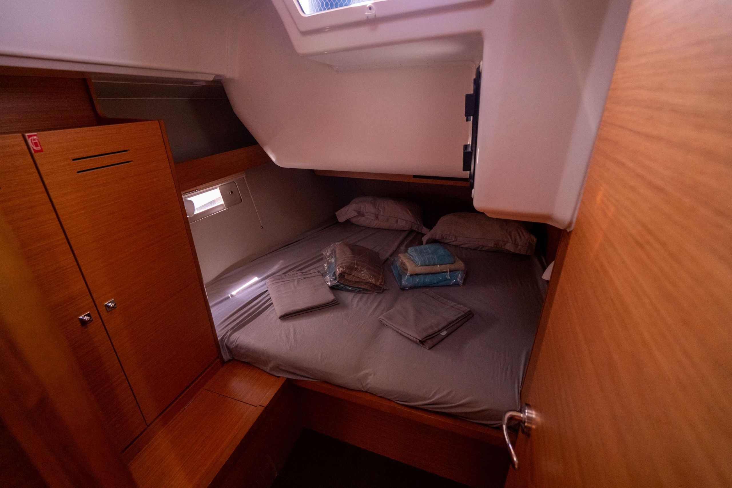 Een knus vakantiehuisje met een stapelbed, een kleine kledingkast en een dakvenster boven het bed.