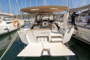 Un bateau nommĂ© « MAELYS » Ă©tait amarrĂ© dans une marina, Ă cĂŽtĂ© dâautres bateaux. On pouvait y voir un volant et une petite table recouverte dâun auvent.