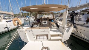 A boat named 'MAELYS' docked at a marina with other boats, a steering wheel, and a small table with a canopy. - Sun-Kissed Sailing Adventure in Provence-Alpes-Côte d'Azur (Saint-Mandrier-sur-Mer)