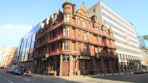A corner building with a traditional facade, a prominent turret, and a modern glass extension. - Stylish 2BR Apt | Walk to New Street & Colmore Row (Birmingham)