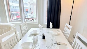 A dining table set with white plates, glasses, and cutlery, with a window view of a city street. - Stylish 2BR Apt | Walk to New Street & Colmore Row (Birmingham)