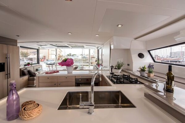 A modern kitchen with a central island, stainless steel sink, and a view of the marina outside.