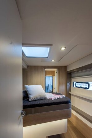 A compact, modern interior with a skylight, a bed with a pillow, and a small window.