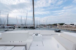 A marina with multiple sailboats docked, a clear sky, and a calm water surface.