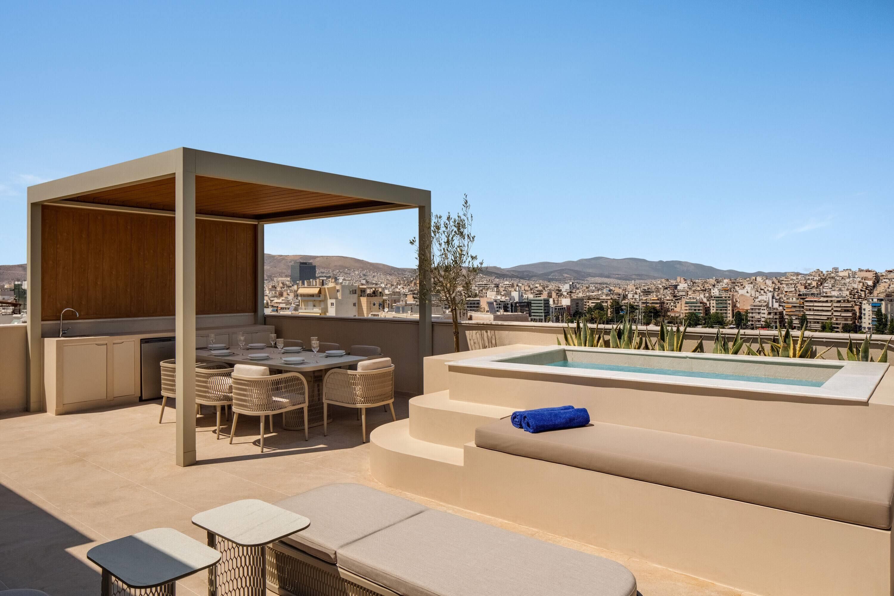 Una terraza en la azotea con piscina, zona de estar y bar.