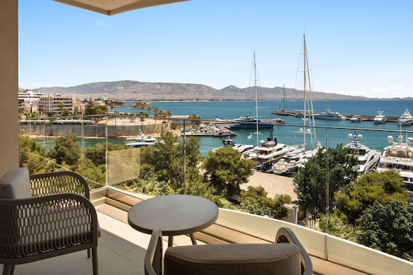 A balcony with a table and chairs overlooking a marina with yachts and boats.
