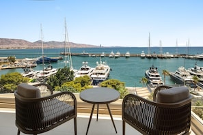 A marina with multiple yachts docked, a view of the sea, and a table with chairs in the foreground. - Wyndham Residences Piraeus Marina Zeas (Piraeus)