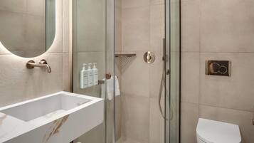 A modern bathroom with a glass shower enclosure, a white sink, and a toilet.
