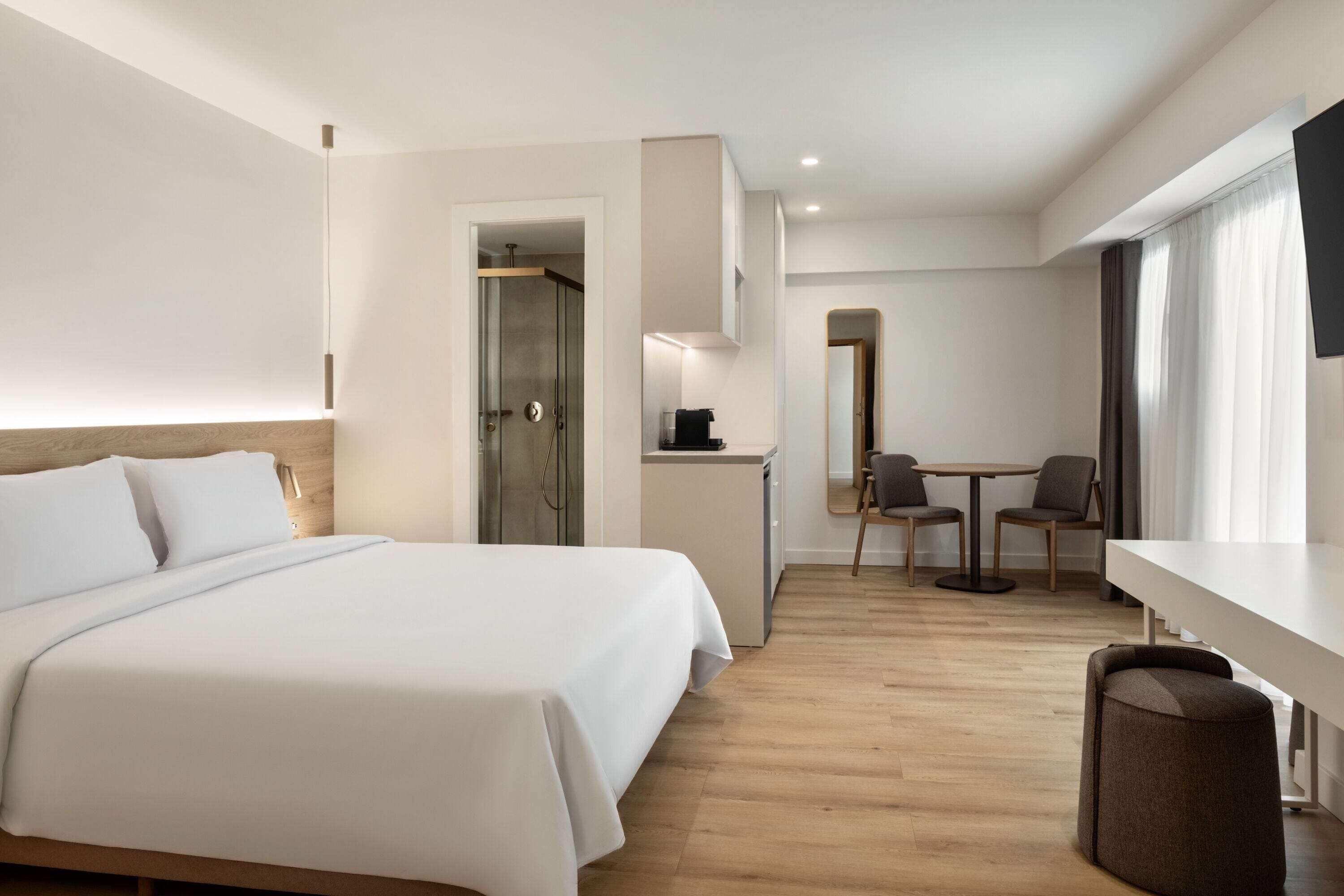 A hotel room with a bed, a desk, a chair, and a television.