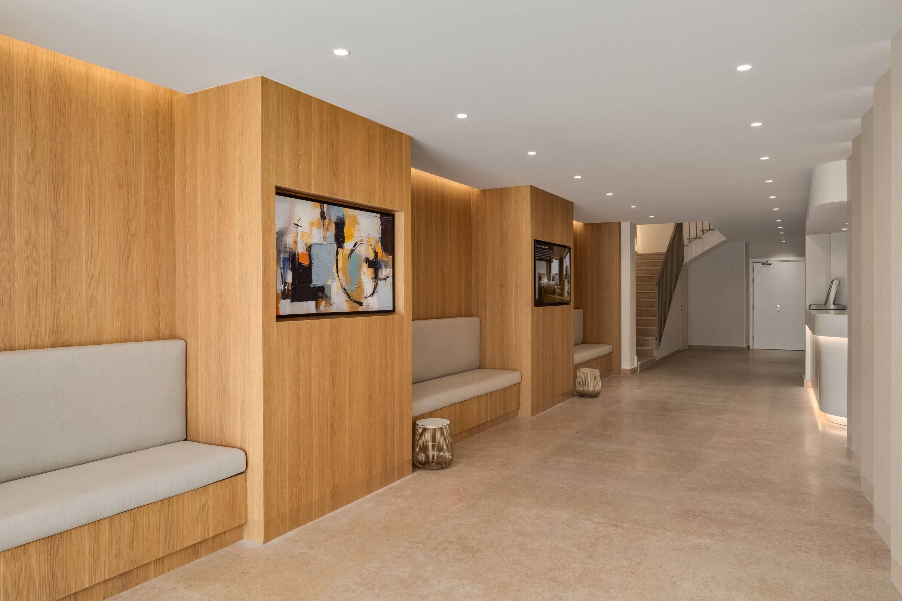 A modern interior with wooden paneling, a seating area, and a staircase leading to another level.