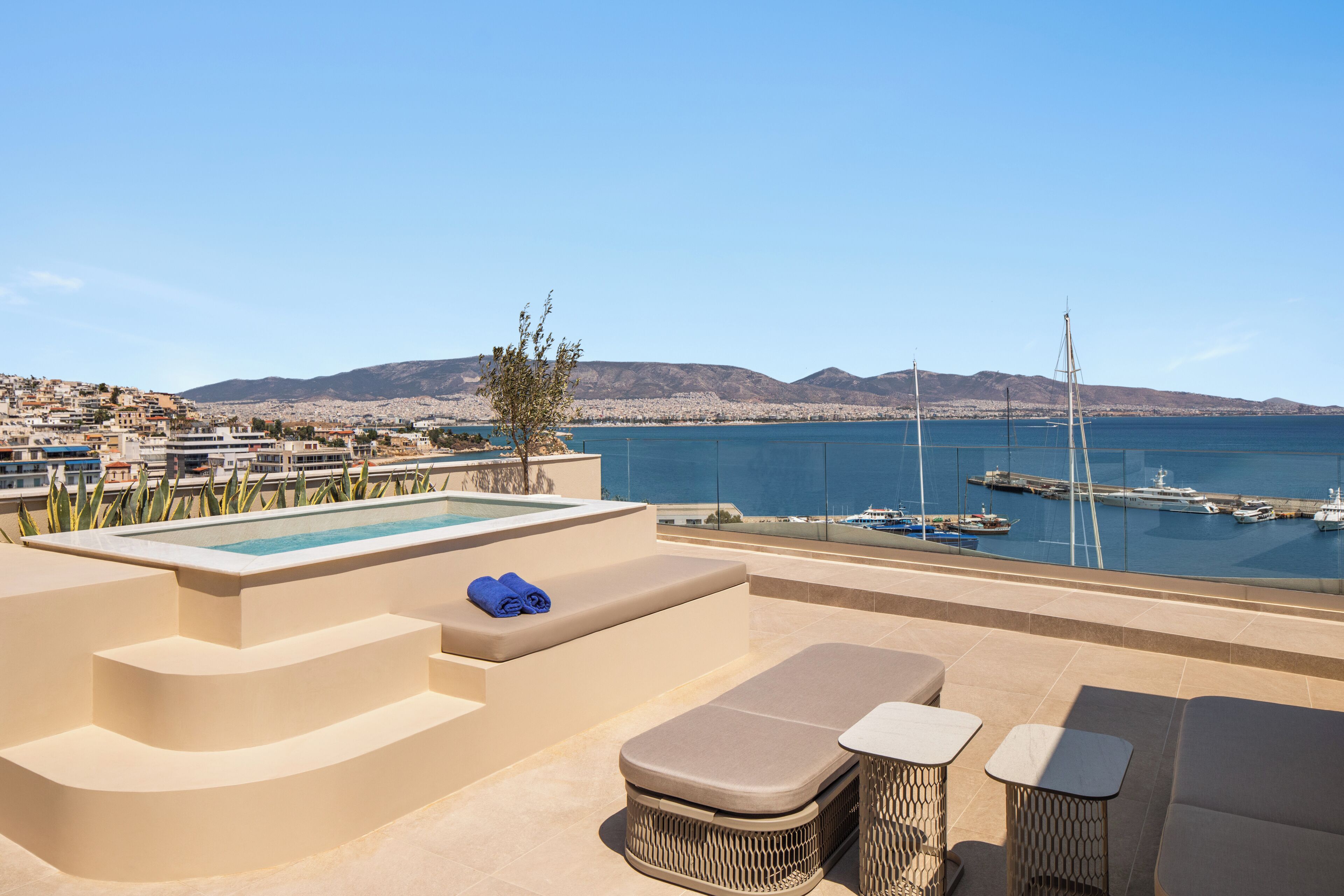 Terraza en la azotea con piscina, mobiliario y vistas al mar y al paisaje urbano.