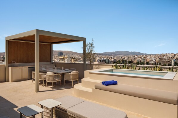 A rooftop terrace with a dining area, a pool, and a view of a cityscape.
