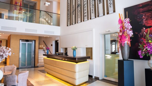 Eine moderne Hotellobby mit einer Rezeption, einer Treppe und einem großen abstrakten Gemälde.