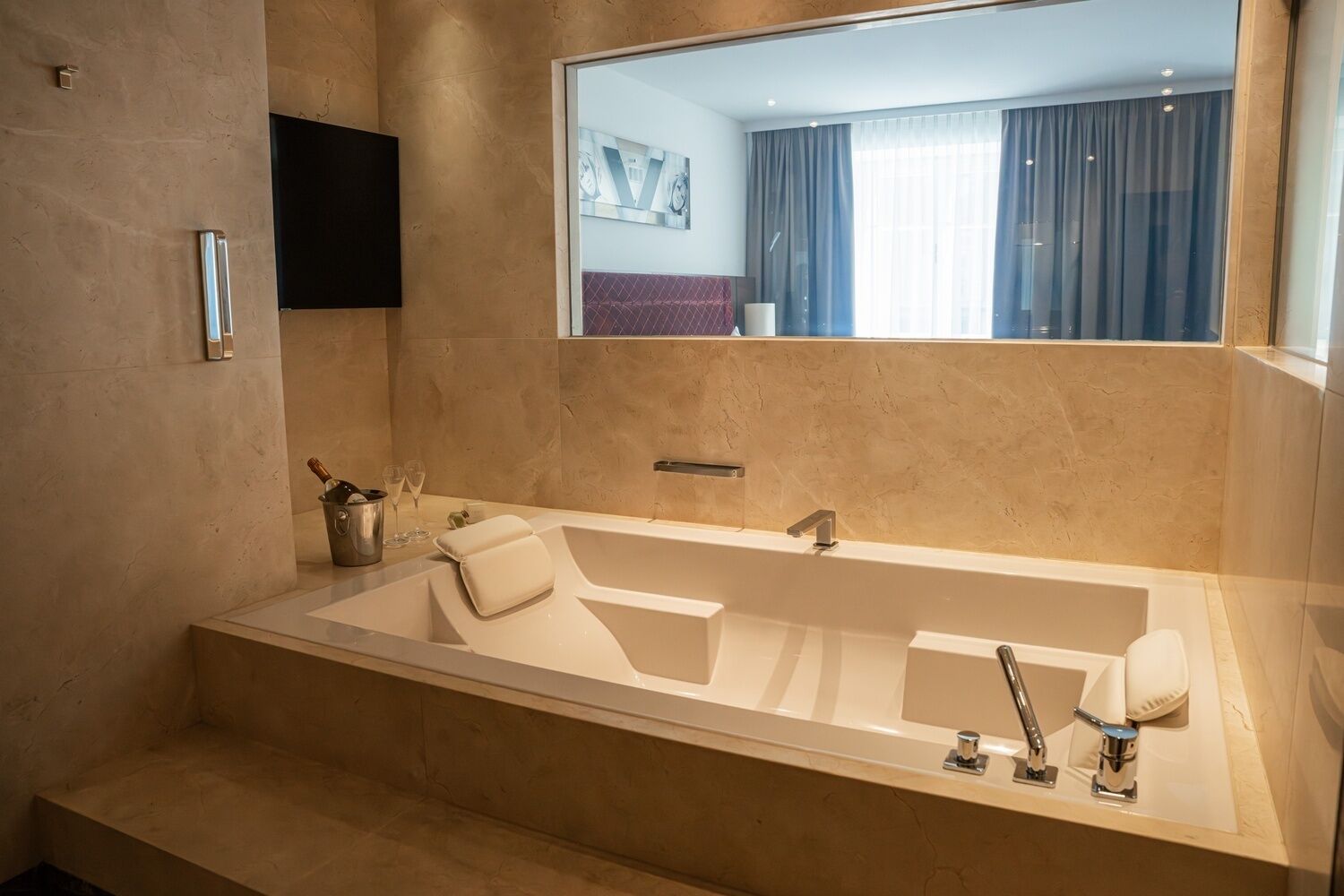 Un baño moderno con una bañera grande, un espejo y un lavamanos.