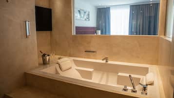 Un baño moderno con una bañera grande, un espejo y un lavamanos.
