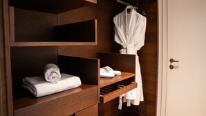 Ein Holzkleiderschrank mit Einlegeböden, einer Kleiderstange und einem gefalteten Handtuch.