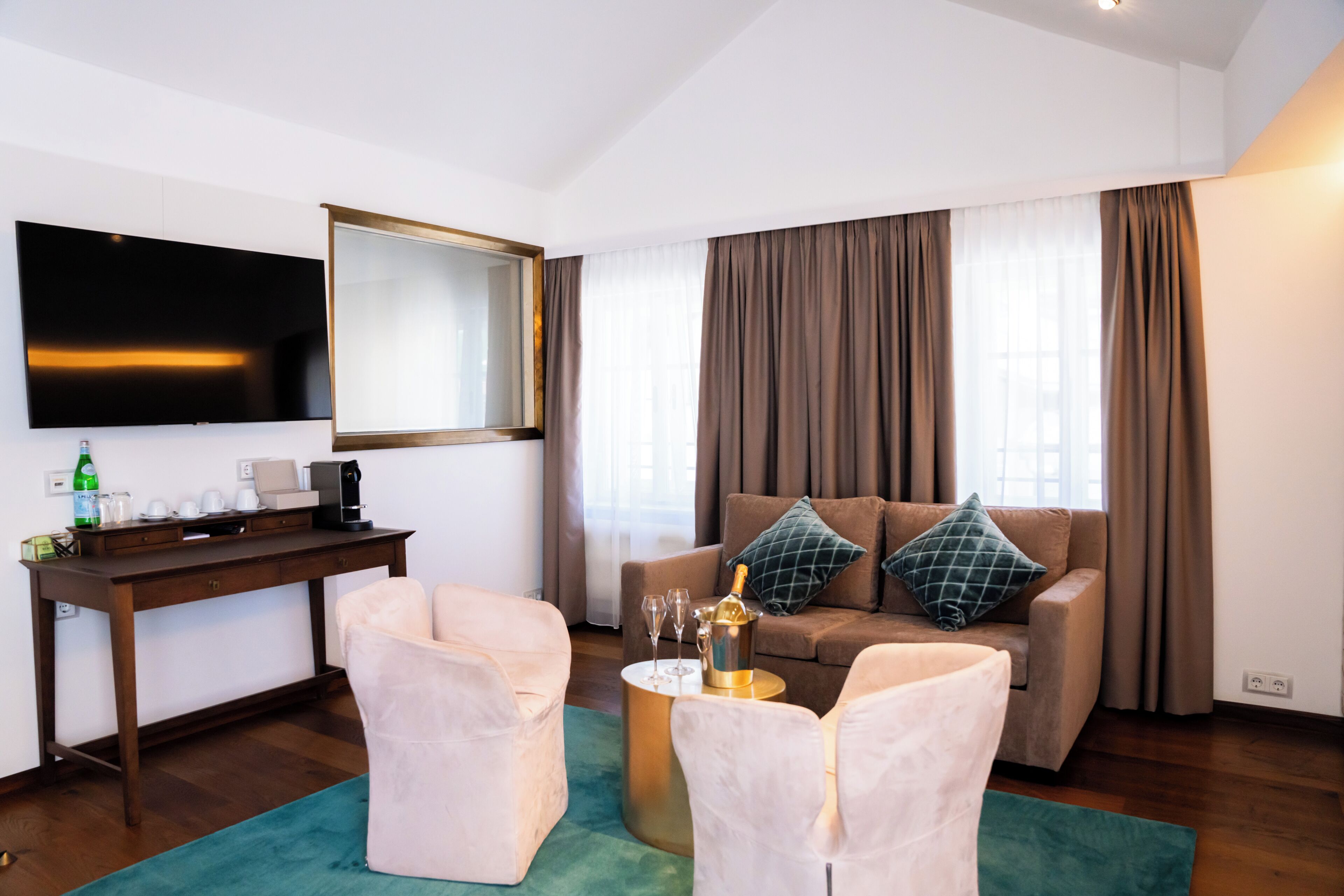 Ein modernes Wohnzimmer mit Fernseher, Schreibtisch aus Holz, einer Couch mit Kissen und einer Kaffeemaschine.