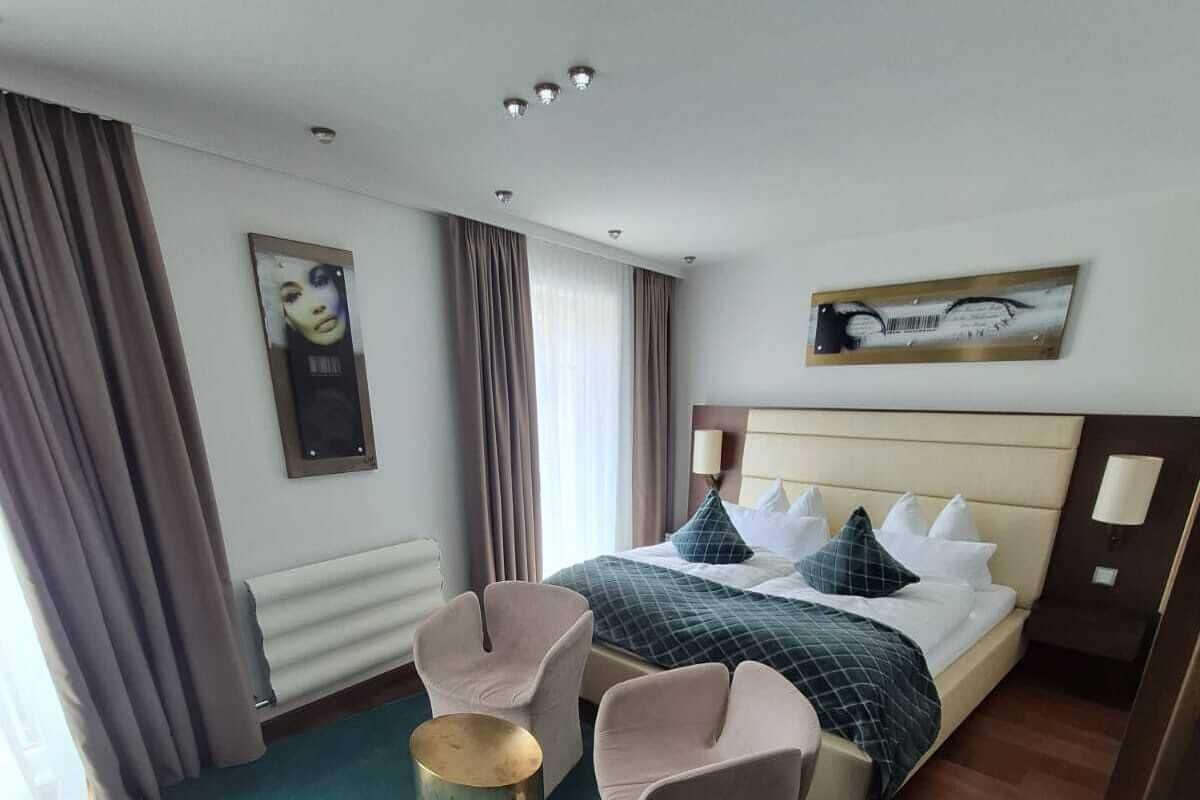 A hotel room with a bed, two armchairs, a small round table, and a painting on the wall.