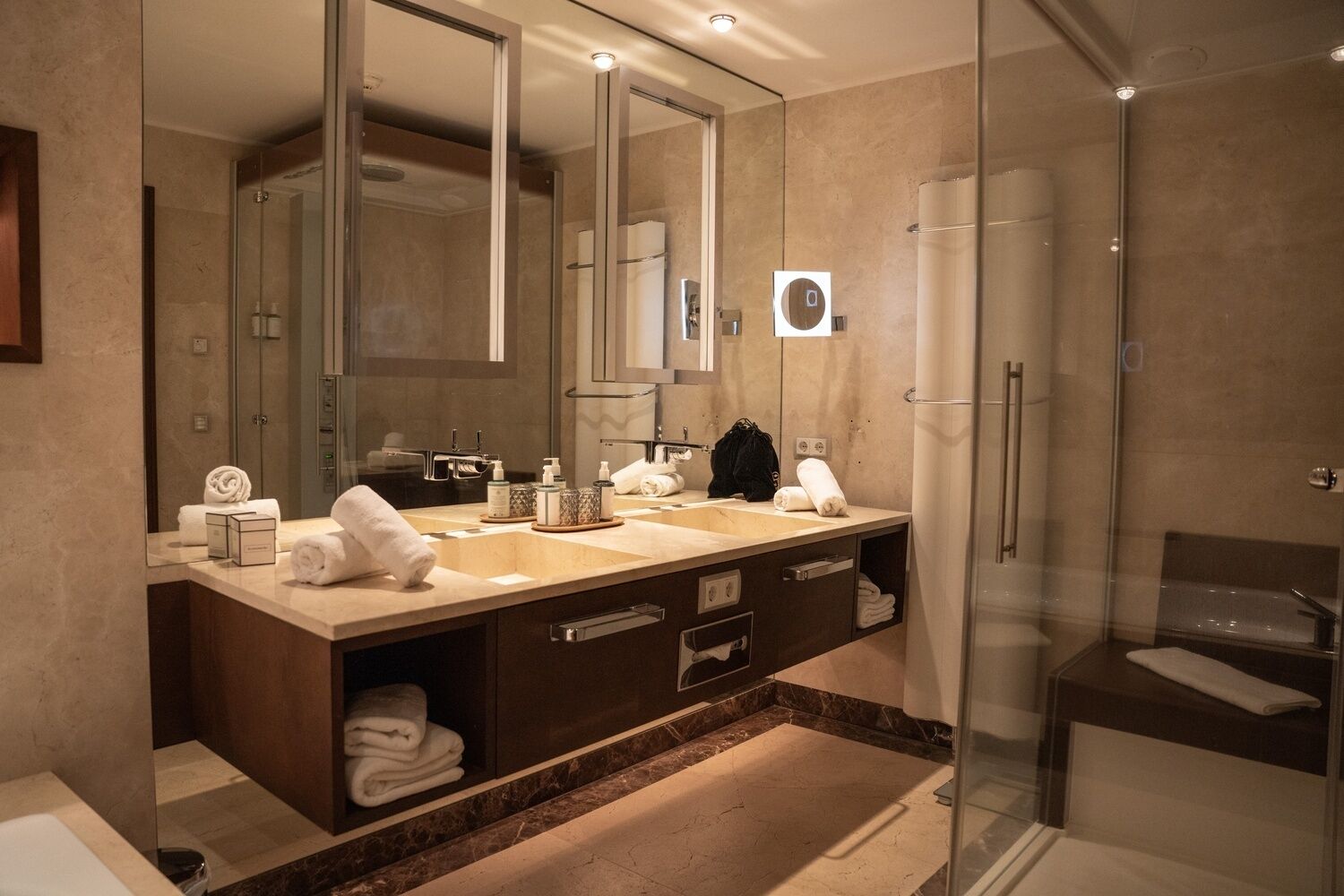 Un baño moderno con un espejo grande, dos lavamanos, una ducha y cabina de ducha acristalada.