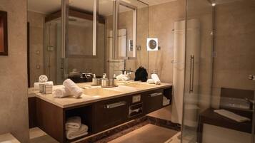 Un baño moderno con un espejo grande, dos lavamanos, una ducha y cabina de ducha acristalada.