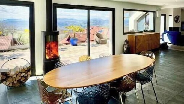Een moderne eetruimte met een grote houten tafel, vier stoelen en een open haard.