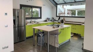 Een moderne keuken met een groot eiland, roestvrijstalen apparatuur en een dakraam.