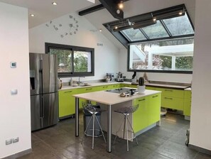 A modern kitchen with a large island, stainless steel appliances, and a skylight.
