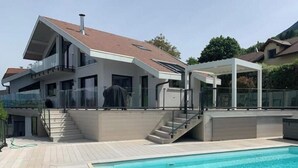 Een modern huis met twee verdiepingen, een zwembad, een overdekt terras en een trap naar de bovenverdieping.