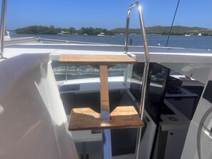 A boat's interior with a wooden shelf, a metal railing, and a control panel.