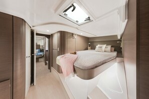 Une chambre à coucher moderne avec un puits de lumière, un lit recouvert d’une couverture rose, une table de chevet et une armoire.