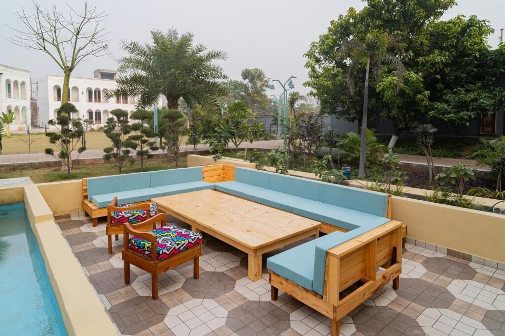 A poolside area with a wooden bench and chairs, a small table, and a pool.