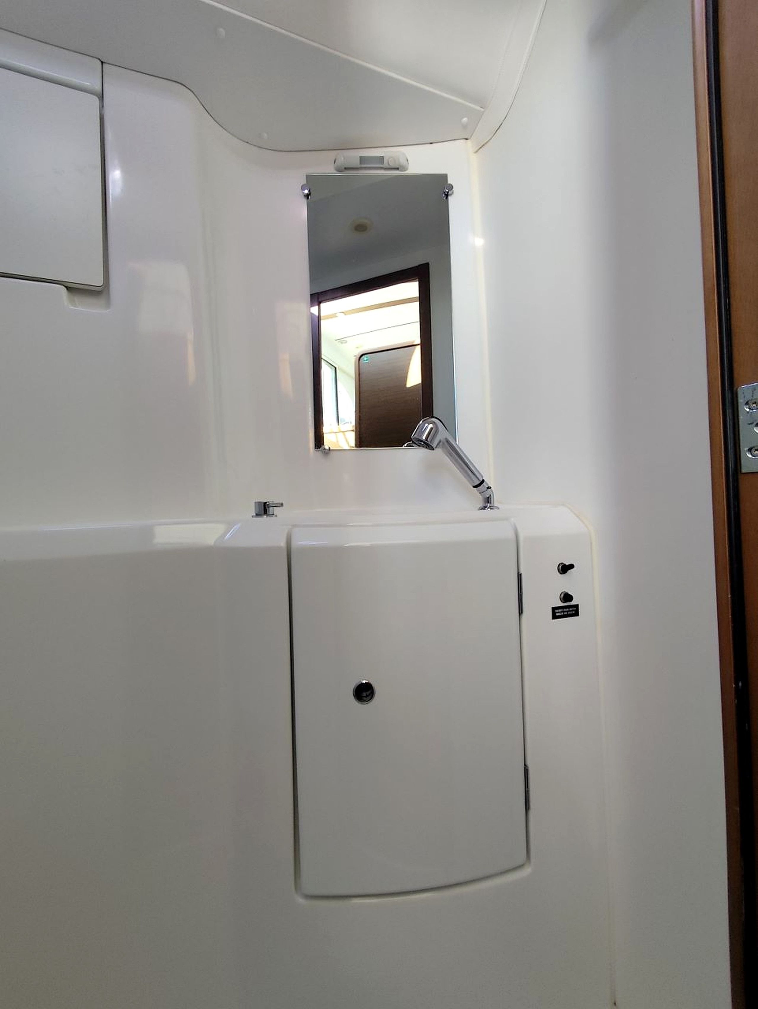 A compact bathroom with a white sink, a mirror, and a small window.