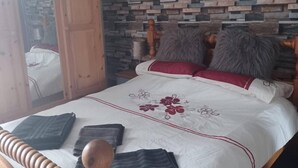 A bedroom with a wooden headboard, a stone wall, and a bed with a floral bedspread. - 1 Apartment Sleeps 2 (Sutton-in-Ashfield)