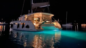 A yacht with a large deck, a swimming pool, and a well-lit interior. - Sun-Kissed Sailing Adventure in Islas Sarónicas (Alimos)