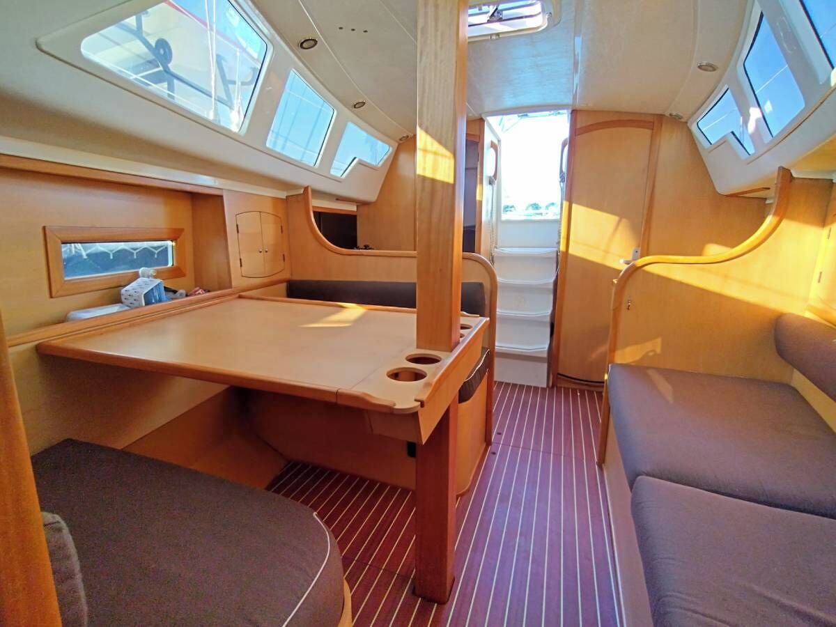 A compact interior with a wooden table, cushioned seating, and skylights.