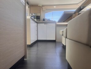 Une cuisine compacte dotée d’un four et d’un micro-ondes encastrés, d’un petit plan de travail et offrant une vue sur le ciel grâce à une lucarne.