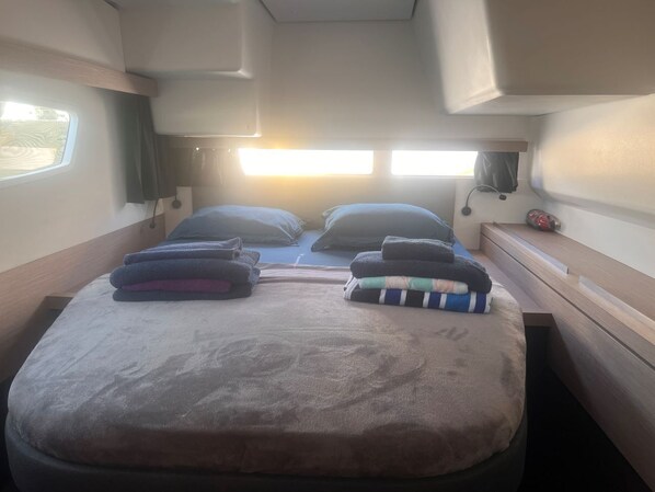 A compact RV interior with a bed, two windows, and a small table. - Caribbean Dream: Sun-soaked Sailing Adventure from Tortola, Islas Vírgenes Británicas (Parham Town)