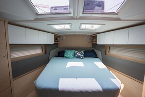 Ein kompakter, gut beleuchteter Raum mit einem Bett, Dachfenstern und Einbauschränken.