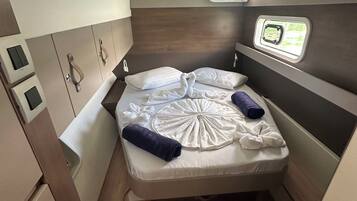 Ein kleines Schlafzimmer mit Bett, kleinem Fenster und Bedienfeld.