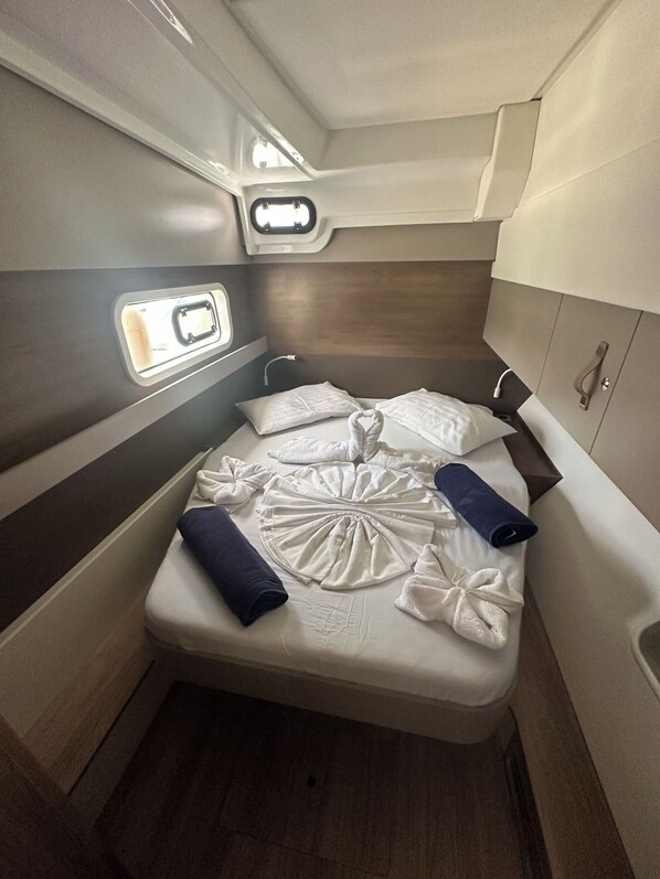 A compact, well-lit cabin with a single bed, a small window, and a built-in storage cabinet.