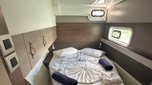 Ein gemütliches, helles Kabinett mit einem Einzelbett, Stauraumschränken und einem kleinen Fenster.