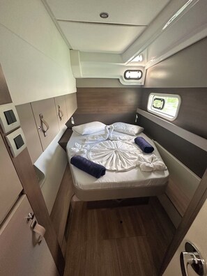 Ein gemütliches, helles Kabinett mit einem Einzelbett, Stauraumschränken und einem kleinen Fenster.