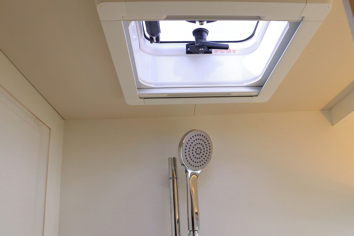 A skylight with a showerhead and hose in a room.
